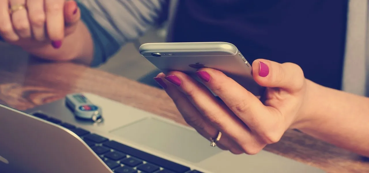 woman at desk reading news on phone